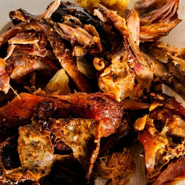 Close-up of a pile of cooked, shredded meat and bones on a white plate.